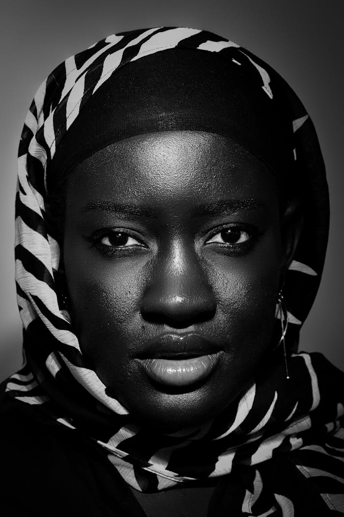 A captivating black and white portrait of a woman in a patterned veil exuding confidence.